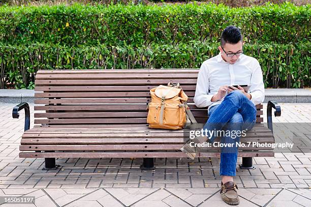young man using digital tablet in park. - sitting bench stock pictures, royalty-free photos & images