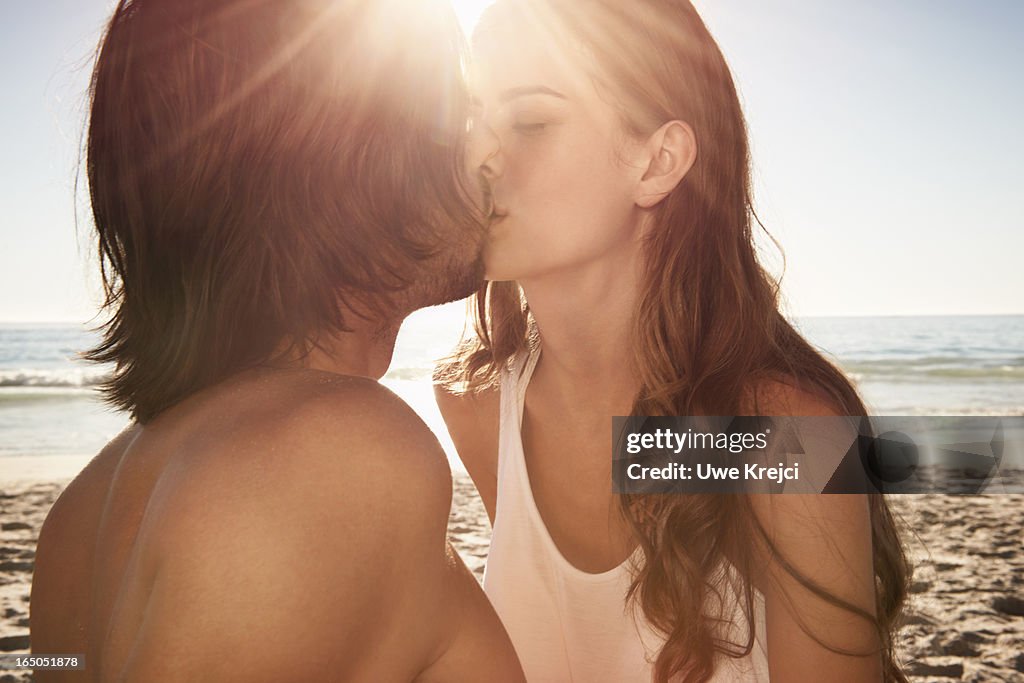 Young couple kissing on beach at sunset