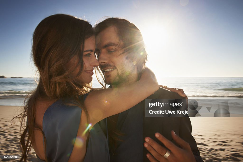 A young couple embracing on beach at sunset