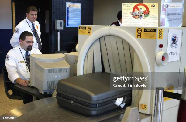 Transportation Security Agency employees Philip Calderon and George Prescott monitor a piece of checked baggage as it passes through an InVision CTX...
