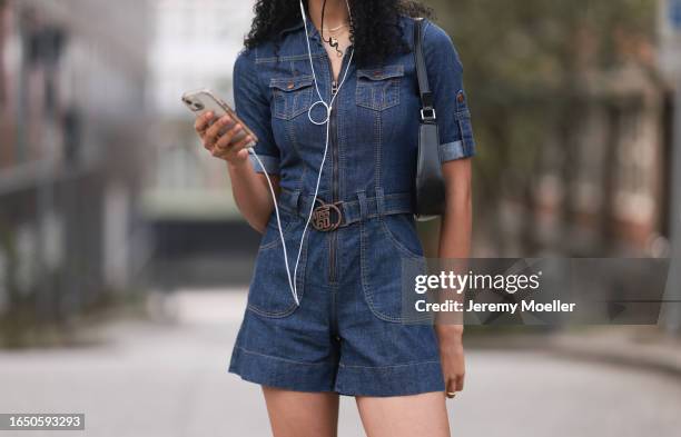 Bella Jürgensen seen wearing dark blue denim jumpsuit / short overall, black shiny leather shoulder bag, on August 25, 2023 in Hamburg, Germany.