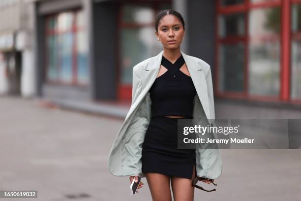 Annabelle Müller seen wearing gold earrings, brown tortoise sunglasses, black knit tank top, white cream blazer jacket, black short skirt, on August...