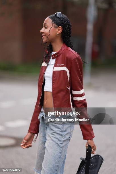 Wendy Brünings seen wearing gold earrings, black sunglasses, white cotton cropped top, iets frans red / white leather biker jacket, light blue denim...