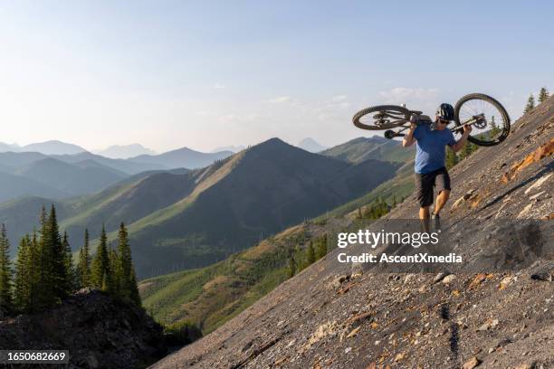 male mountain biker carries bike up steep slope - steep stock pictures, royalty-free photos & images