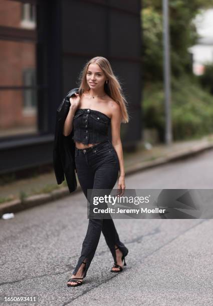 Patricia Lilith Richter seen wearing gold jewelry, black / grey denim corset top, matching black / grey denim long slit pants / jeans, black leather...