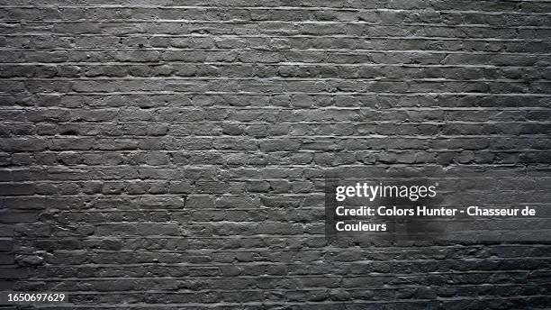 black painted brick wall with natural light and shadows in london, england, united kingdom - bakstenen muur stockfoto's en -beelden