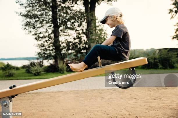 little boy on seesaw - wippe stock-fotos und bilder