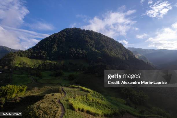 aerial view of a beautiful mountain near jardin, antioquia, colombia surrounded by hills, farmlands and forests at dawn - colombia mountains stock pictures, royalty-free photos & images