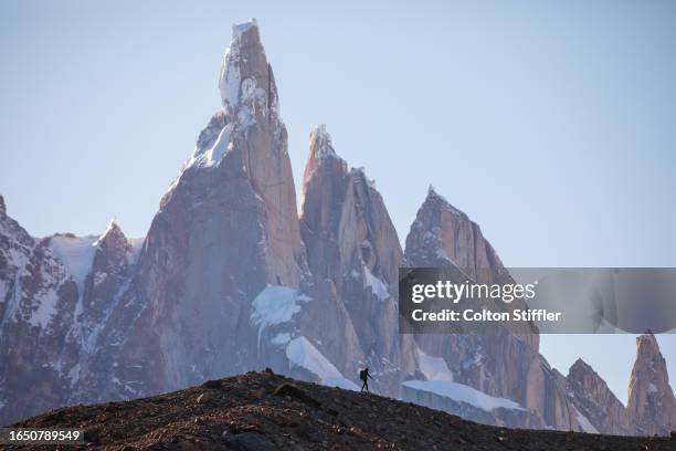 a hiker silhouetted against the massive peaks of cerro torre in los glaciares - cerro torre - fotografias e filmes do acervo