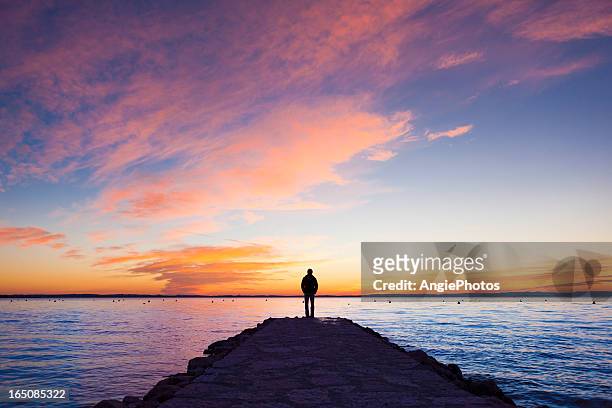 uomo in piedi sul molo - sunset foto e immagini stock