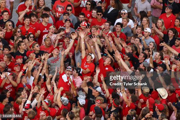 Fans reach for a volleyball thrown by a Nebraska Cornhusker during player introductions before the game between the Nebraska Cornhuskers and the...