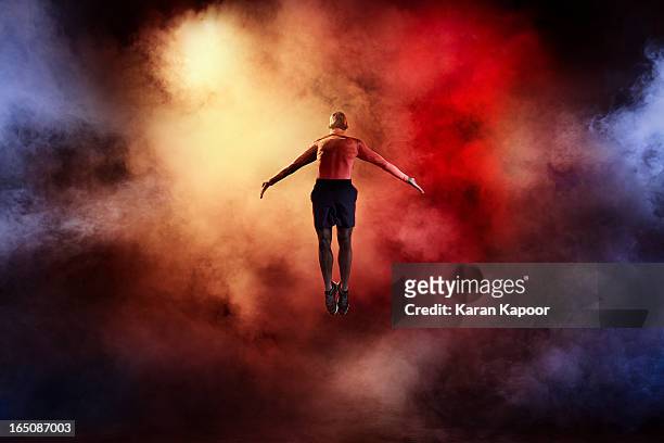 male athlete leaping with arms streched - dry ice stock pictures, royalty-free photos & images