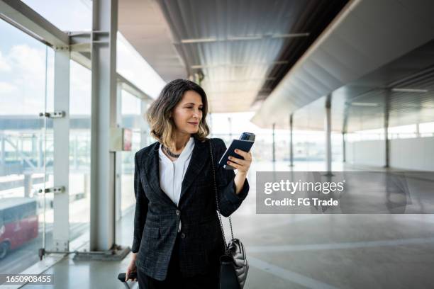 geschäftsfrau, die zu fuß geht, während sie das telefon am flughafen benutzt - einzelne frau über 40 stock-fotos und bilder