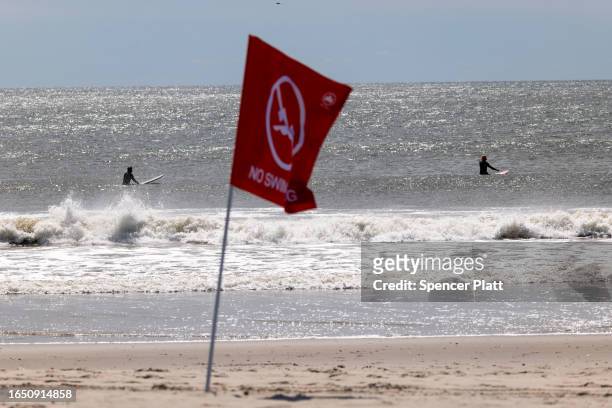 Surfers ride waves at Rockaway Beach in New York as high surf from Hurricane Franklin delivers strong rip tides and large waves to most of the...