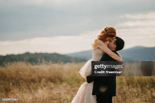 schönes gerade verheiratetes paar küsst sich in der natur - hochzeitspaar stock-fotos und bilder