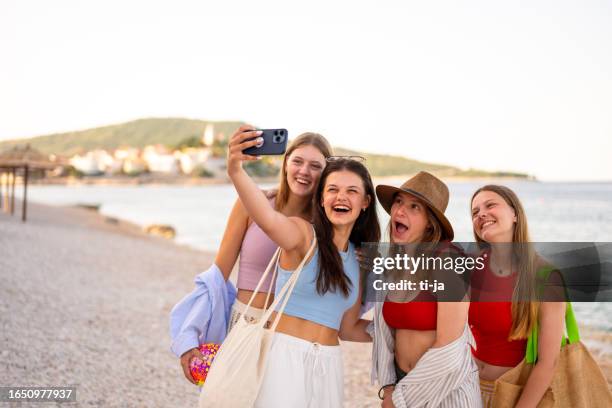 four teenage girls taking a selfie with a mobile phone on the beach in summertime - beach selfie bildbanksfoton och bilder