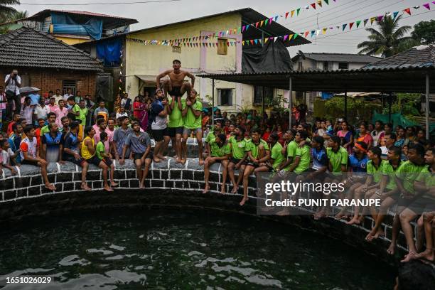 Hindu devotees prepare to break the dahi-handi, curd-pot, suspended in the air above a water well during celebrations of Janmashtami, which marks the...