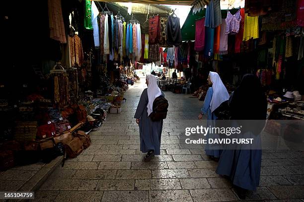 Christian pilgrims walk amid shops along the Via Dolorosa, believed to be the path that Jesus walked as he bore his cross to the site of his...
