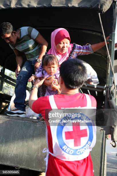 Philippine National Red Cross worker carries a child displaced by continuing armed conflict between the supporters of Philippine Muslim clan Sulu...
