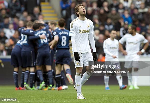 Swansea City's Spanish midfielder Miguel Michu reacts after Tottenham Hotspur players celebrate their opening goal during the Premiership match at...