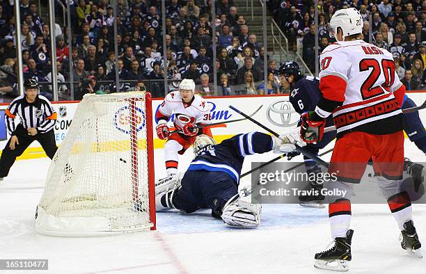Riley Nash of the Carolina Hurricanes watches as teammate Jussi Jokinen shoots the puck into the net past goaltender Ondrej Pavelec of the Winnipeg...