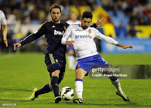 Gonzalo Higuain of Real Madrid competes for the ball with Alvaro Gonzalez of Real Zaragoza during the La Liga match between Real Zaragoza and Real...