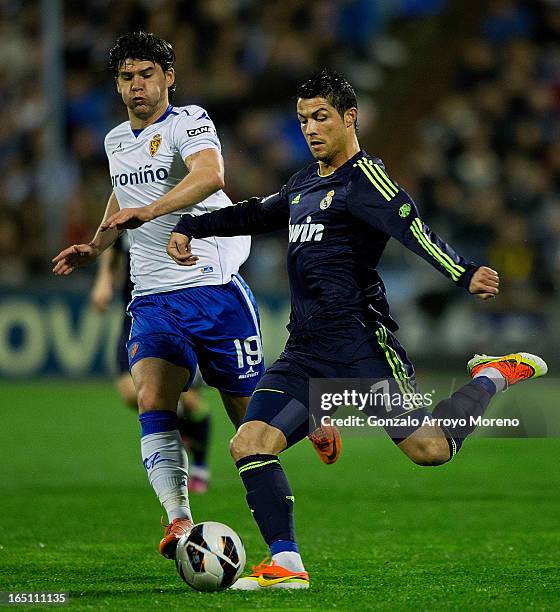 Cristiano Ronaldo of Real Madrid CF competes for the ball with Cristian Sapunaru of Real Zaragoza during the La Liga match between Real Zaragoza and...