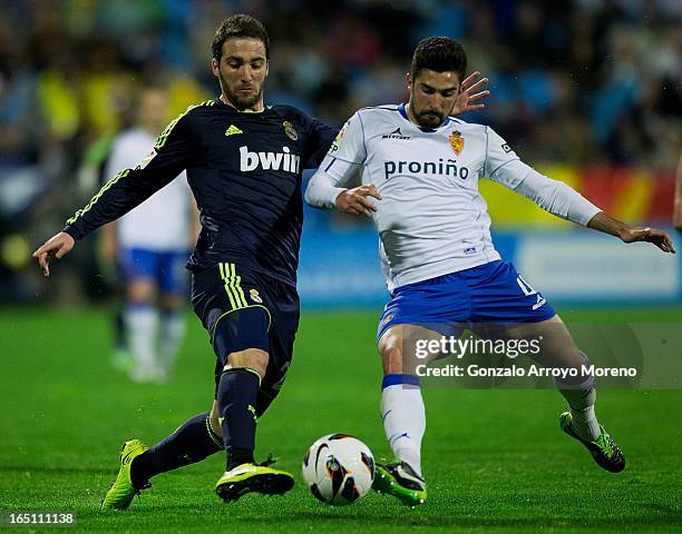 Gonzalo Higuain of Real Madrid CF competes for the ball with Clvaro Gonzalez Soberon of Real Zaragoza during the La Liga match between Real Zaragoza...