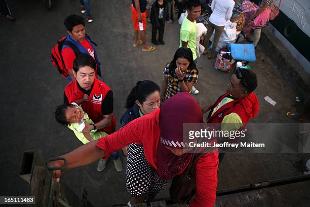 Government social welfare officer carries a child displaced by continuing armed conflict between the supporters of Philippine Muslim clan Sulu Sultan...