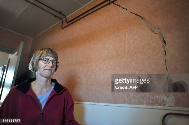 Netherland's Martha Bos poses in front of a crack in her wall on March 12, 2013 in Middelstum, some 10km from Groningen, caused by repeated...