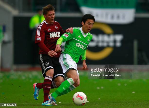 Makoto Hasebe of Wolfsburg and Mike Frantz of Nuernberg compete for the ball during the Bundesliga match between VfL Wolfsburg and 1. FC Nuernberg at...