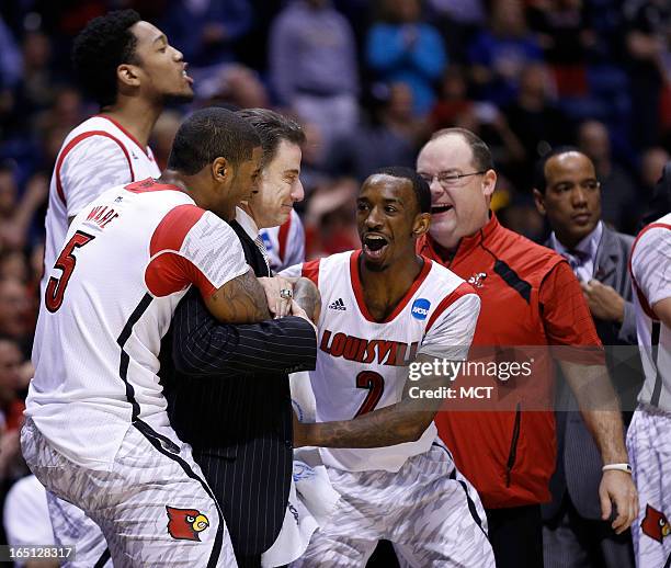 Louisville head coach Rick Pitino is embraced by his team, including Louisville guard Russ Smith at the end of the game in the NCAA regional final...