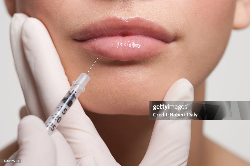 Close up of woman receiving botox injection in lips