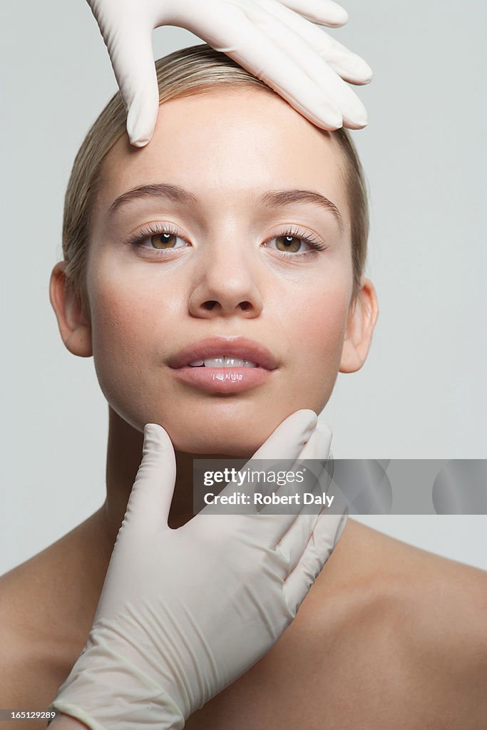 Close up of rubber-gloved hands touching womans face