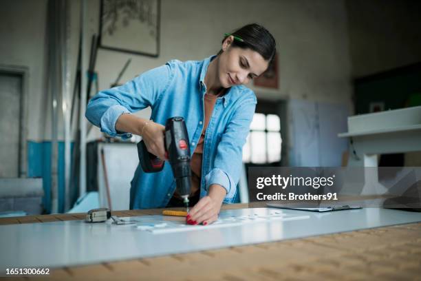 young woman fitting a template over acrylic sheet using cordless screwdriver in workshop - cordless drill stock pictures, royalty-free photos & images