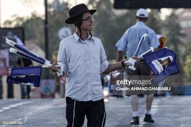 An Orthodox Jewish demonstrator hands out miniature flags of the "Third Temple" movement during a rally in support of the Israeli government's...