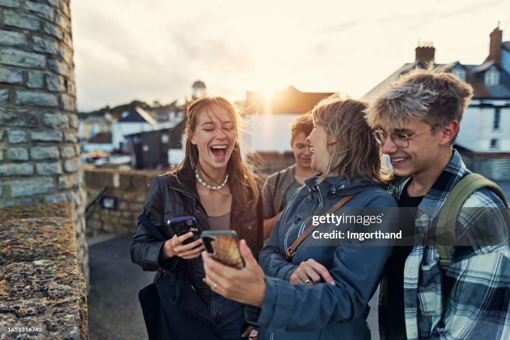 Mutter und drei Teenager besichtigen die Stadt Lyme Regis, Dorset, an einem Sommertag