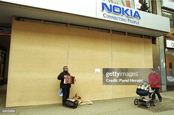 Blind entertainer plays his accordion in front of a boarded up Nokia store November 20, 2002 in central Prague, Czech Republic. The city is bracing...