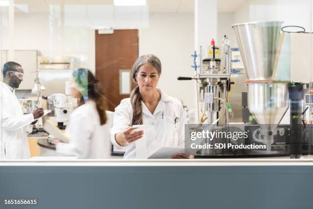 scientist reads the test results to update her lab report - science research stock pictures, royalty-free photos & images