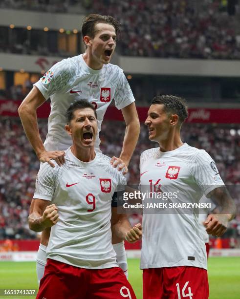 Poland's forward Robert Lewandowski celebrates after scoring a penalty with Poland's midfielder Jakub Kaminski and Poland's defender Jakub Piotr...