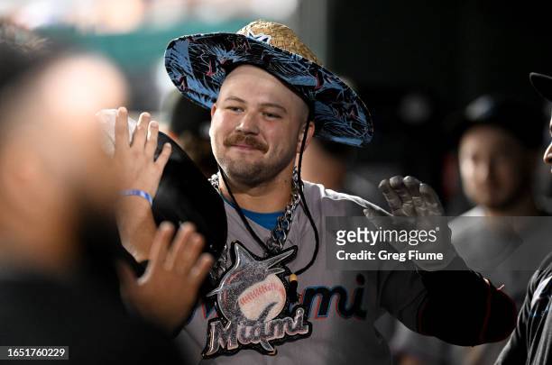 Jake Burger of the Miami Marlins celebrates with teammates in the dugout after hitting a home run in the ninth inning against the Washington...