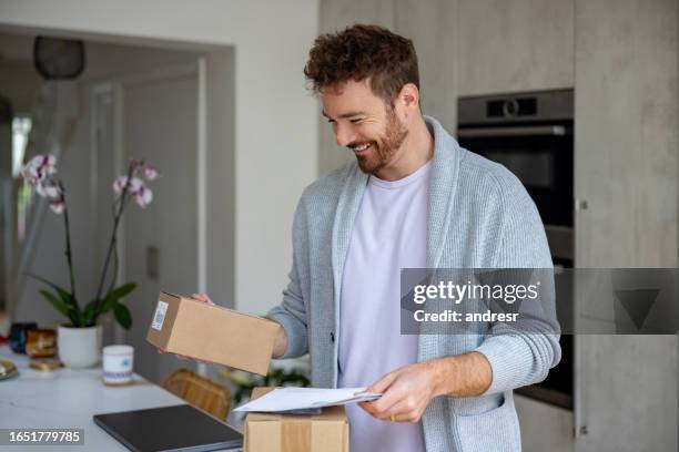 happy man at home checking the mail and reading a letter - enviar imagens e fotografias de stock
