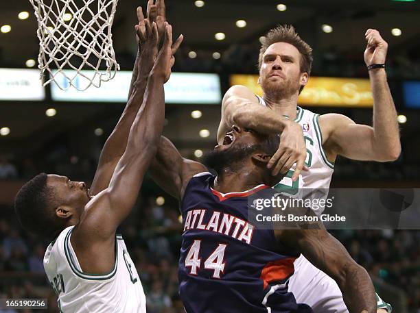 Boston Celtics power forward Shavlik Randolph makes contact with Atlanta Hawks power forward Ivan Johnson after seating away a shot attempt by...