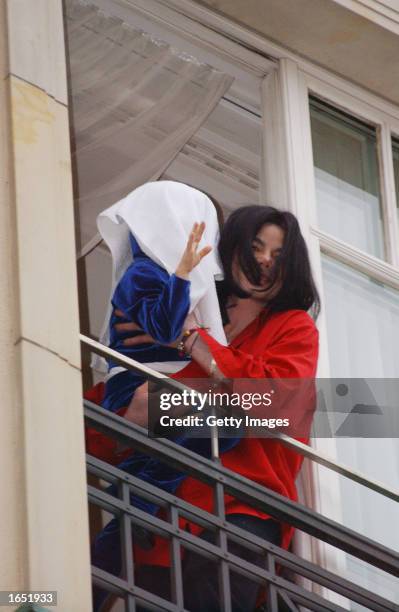 Singer Michael Jackson appears at the balcony of the Adlon Hotel with an unidentified child November 19, 2002 in Berlin, Germany. Jackson is in...