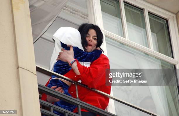Singer Michael Jackson appears at the balcony of the Adlon Hotel with an unidentified child November 19, 2002 in Berlin, Germany. Jackson is in...