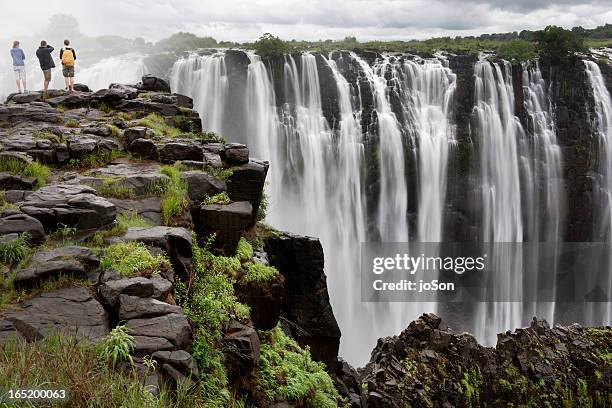three people looking at victoria falls, zimbabwe, - zimbabwe stockfoto's en -beelden