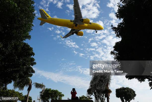 Person takes a photo of a Spirit Airlines plane landing from a park next to Los Angeles International Airport on August 31, 2023 in Los Angeles,...