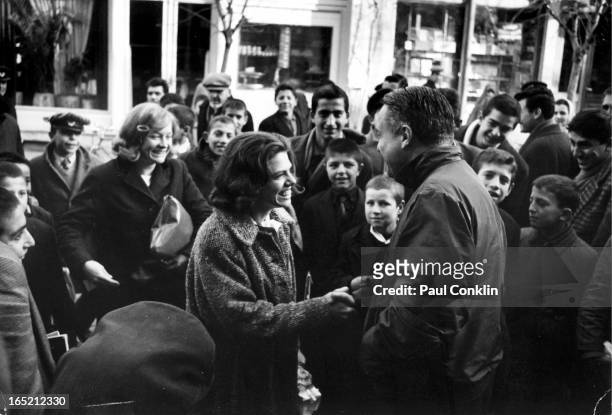 Peace Corps founder and president Sargent Shriver greets Peace Corps volunteers Kathy Campbell and Betty Hanks as they walked with their students...
