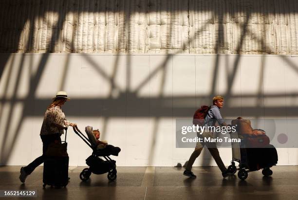 Travelers walk with luggage in the international terminal at Los Angeles International Airport on August 31, 2023 in Los Angeles, California. Labor...