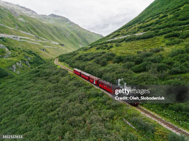 aerial view of steam train passing alpine meadow in swiss alps - locomotiva imagens e fotografias de stock